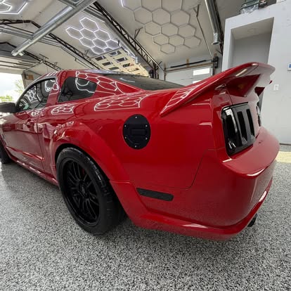 Tinted red Mustang in the illuminated J&J Express Services shop